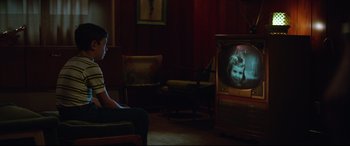 Movie still from “Suburbicon” (2017), directed by George Clooney – A man sitting in front of an old television; Medium shot, Over the shoulder angle