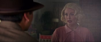 Movie still from “Suburbicon” (2017), directed by George Clooney – A woman in a pink dress is talking to a man in a hat; Medium shot, Over the shoulder angle