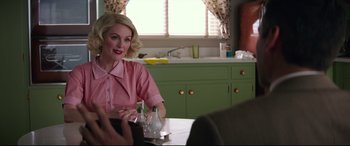 Movie still from “Suburbicon” (2017), directed by George Clooney – A woman sitting at a table in front of a sink; Medium shot, Over the shoulder angle