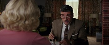 Movie still from “Suburbicon” (2017), directed by George Clooney – A man in a suit and tie sitting in front of a woman; Medium shot, Over the shoulder angle