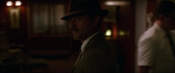 Movie still from “Suburbicon” (2017), directed by George Clooney – A man in a suit and a hat is smiling; Close Up shot, Over the shoulder angle