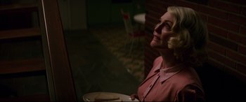 Movie still from “Suburbicon” (2017), directed by George Clooney – A woman sitting in front of a plate with a sandwich; Medium shot, Low angle