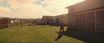 Movie still from “Suburbicon” (2017), directed by George Clooney – A man standing in a yard holding a frisbee; Extreme Wide shot, High angle
