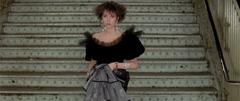 Movie still from “Subway” (1985), directed by Luc Besson – A woman in a black top is standing on some steps; Medium shot, Low angle