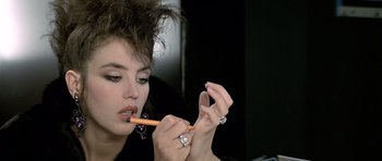 A woman is holding an orange pencil in her mouth