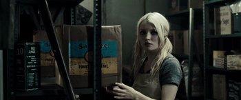 Movie still from “Sucker Punch” (2011), directed by Zack Snyder – A woman holding a bag of food in a room; Close Up shot, Over the shoulder angle