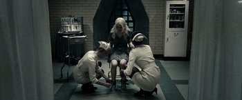 Movie still from “Sucker Punch” (2011), directed by Zack Snyder – A group of people in a room with a woman sitting on a chair; Wide shot, High angle