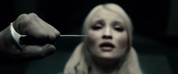 Movie still from “Sucker Punch” (2011), directed by Zack Snyder – A woman is holding a needle in her mouth; Extreme Close Up shot, Over the shoulder angle