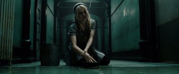 Movie still from “Sucker Punch” (2011), directed by Zack Snyder – A woman sitting on the ground in a dark room; Medium shot, High angle