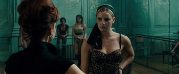 Movie still from “Sucker Punch” (2011), directed by Zack Snyder – A woman in a leopard print dress and a black head scarf; Medium shot, Over the shoulder angle