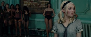 Movie still from “Sucker Punch” (2011), directed by Zack Snyder – A group of women standing next to each other in a room; Medium shot, Over the shoulder angle