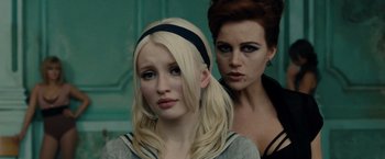 Movie still from “Sucker Punch” (2011), directed by Zack Snyder – Two women standing next to each other in front of a green wall; Close Up shot, Over the shoulder angle