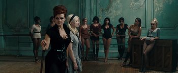 Movie still from “Sucker Punch” (2011), directed by Zack Snyder – A group of women standing next to each other in front of a wall; Wide shot, High angle