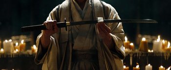 Movie still from “Sucker Punch” (2011), directed by Zack Snyder – A man in a robe holding a sword in his hands; Close Up shot, High angle