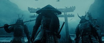 Movie still from “Sucker Punch” (2011), directed by Zack Snyder – A man in a hat and armor holding a sword; Medium shot, Low angle