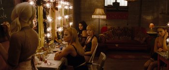Movie still from “Sucker Punch” (2011), directed by Zack Snyder – A group of women sitting at a table in front of a mirror; Medium shot, Over the shoulder angle