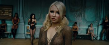 Movie still from “Sucker Punch” (2011), directed by Zack Snyder – A woman with long blonde hair wearing a see - through top; Close Up shot, Over the shoulder angle