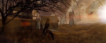 Movie still from “Sucker Punch” (2011), directed by Zack Snyder – A woman standing in a field near a bunch of clothes; Wide shot, Low angle