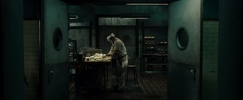 Movie still from “Sucker Punch” (2011), directed by Zack Snyder – A person in a kitchen preparing food on a table; Wide shot, High angle