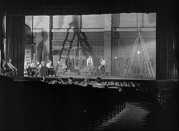 Movie still from “Sudden Fear” (1952), directed by David Miller – A black - and - white photo of a stage with a lot of people sitting on it; Extreme Wide shot, High angle