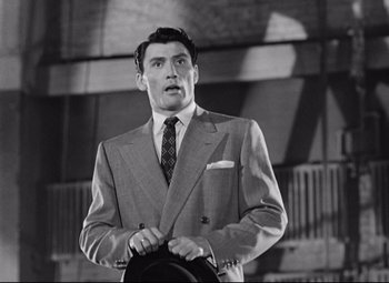 Movie still from “Sudden Fear” (1952), directed by David Miller – A black and white photo of a man in a suit and tie; Medium shot, Low angle