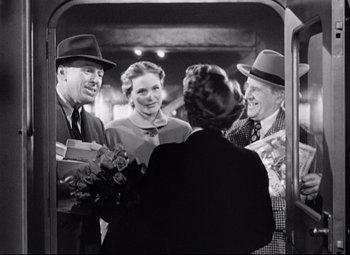 Movie still from “Sudden Fear” (1952), directed by David Miller – A black and white photo of a group of people standing together; Medium shot, Over the shoulder angle