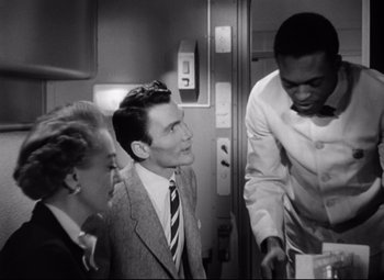 Movie still from “Sudden Fear” (1952), directed by David Miller – A man standing next to two other men in an elevator; Medium shot, Low angle