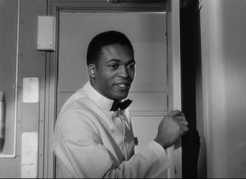 Movie still from “Sudden Fear” (1952), directed by David Miller – A black and white photo of a man wearing a bow tie; Close Up shot, Low angle