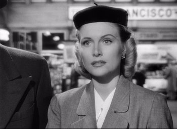 Movie still from “Sudden Fear” (1952), directed by David Miller – A woman in a suit and a hat is looking at the camera; Close Up shot, Low angle