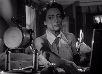 Movie still from “Sudden Fear” (1952), directed by David Miller – An old photo of a woman holding a knife in a room; Close Up shot, Low angle
