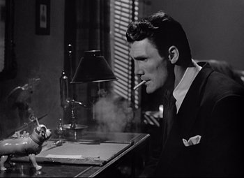 Movie still from “Sudden Fear” (1952), directed by David Miller – A black and white photo of a man smoking a cigarette; Close Up shot, Low angle