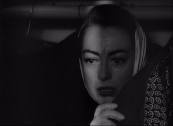 Movie still from “Sudden Fear” (1952), directed by David Miller – A black and white photo of a woman in a car; Close Up shot, Over the shoulder angle