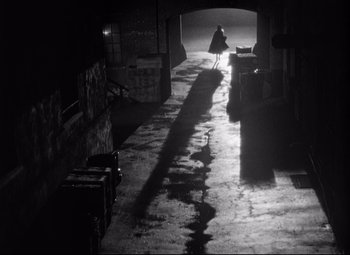 Movie still from “Sudden Fear” (1952), directed by David Miller – A person walking down a street at night; Extreme Wide shot, High angle