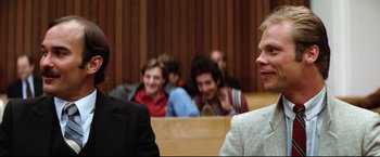 Movie still from “Sudden Impact” (1983), directed by Clint Eastwood – A group of people sitting in a courtroom; Close Up shot, Over the shoulder angle