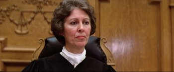 Movie still from “Sudden Impact” (1983), directed by Clint Eastwood – An older woman in a black robe sitting in a chair; Close Up shot, Low angle