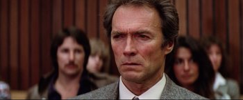 Movie still from “Sudden Impact” (1983), directed by Clint Eastwood – A person wearing a suit and tie; Close Up shot, Low angle