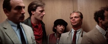 Movie still from “Sudden Impact” (1983), directed by Clint Eastwood – A group of men standing next to each other in front of a wall; Medium shot, Low angle