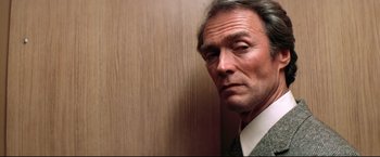 Movie still from “Sudden Impact” (1983), directed by Clint Eastwood – A person wearing a suit near a wall; Close Up shot, Low angle