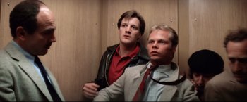 Movie still from “Sudden Impact” (1983), directed by Clint Eastwood – A couple of men standing next to each other in an elevator; Medium shot, Low angle