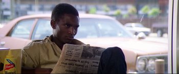 Movie still from “Sudden Impact” (1983), directed by Clint Eastwood – A man reading a newspaper while sitting in a car; Close Up shot, Over the shoulder angle