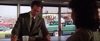 Movie still from “Sudden Impact” (1983), directed by Clint Eastwood – A man sitting at a table in front of a window; Medium shot, Over the shoulder angle