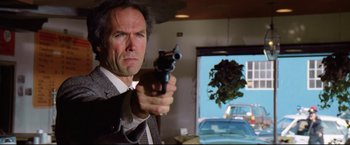 Movie still from “Sudden Impact” (1983), directed by Clint Eastwood – A man holding a gun in front of a mirror; Close Up shot, Low angle