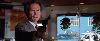 Movie still from “Sudden Impact” (1983), directed by Clint Eastwood – A man in a suit and tie holding a gun; Close Up shot, Low angle