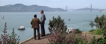 Movie still from “Sudden Impact” (1983), directed by Clint Eastwood – Two men standing on the edge of a cliff overlooking the water; Extreme Wide shot, Over the shoulder angle