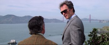 Movie still from “Sudden Impact” (1983), directed by Clint Eastwood – Two men standing next to each other near the ocean; Medium shot, Low angle