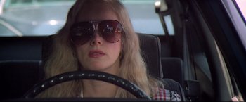 Movie still from “Sudden Impact” (1983), directed by Clint Eastwood – A woman wearing sunglasses sitting in the driver's seat of a car; Close Up shot, Low angle