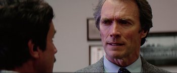 Movie still from “Sudden Impact” (1983), directed by Clint Eastwood – A man in a suit and tie looking at another man in a tie; Close Up shot, Over the shoulder angle