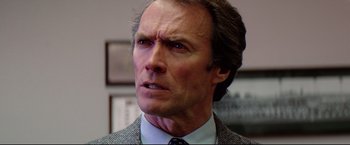 Movie still from “Sudden Impact” (1983), directed by Clint Eastwood – A person wearing a suit and tie; Close Up shot, Low angle