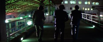 Movie still from “Sudden Impact” (1983), directed by Clint Eastwood – Two men in suits are walking down a walkway; Wide shot, Low angle