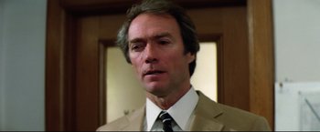 Movie still from “Sudden Impact” (1983), directed by Clint Eastwood – A person wearing a suit and tie; Close Up shot, Low angle